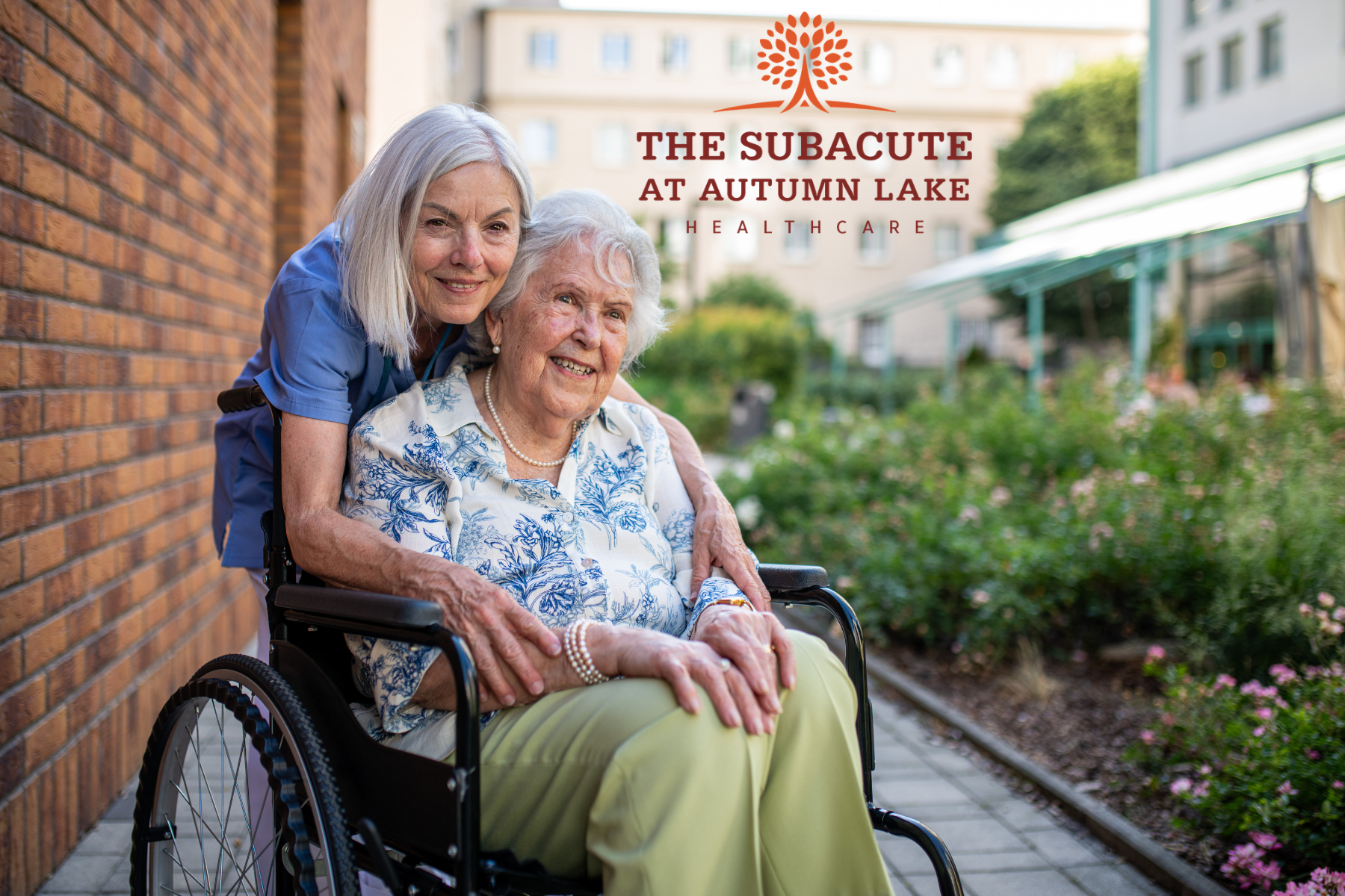 Caregiver embracing a senior woman in a wheelchair outdoors at a nursing home.
